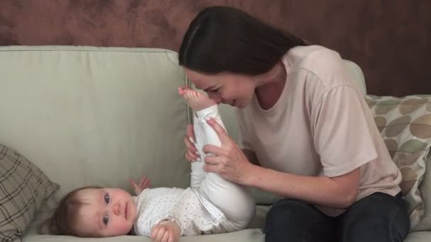 Mãe feliz brincando com o bebê no sofá — Vídeo de Stock