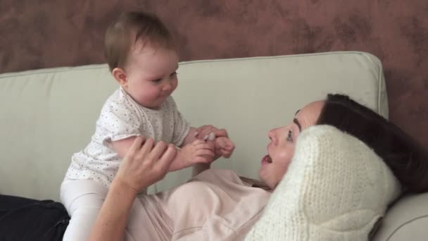 Anya fekszik a kanapén, és megcsókolja imádnivaló baba — Stock videók