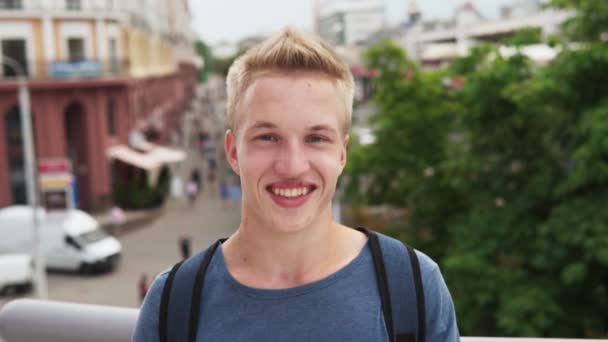 Gülümseyen ve şehir sokak kameraya isteyen genç mutlu erkek öğrenci — Stok video