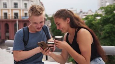 Smartphone vasıl seyir ve kentsel Sokağı'nda gülümseyen iki genç mutlu insanlar