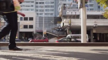 İnsanlar önünde yol canlı araba trafiği olan kentsel cadde boyunca gider