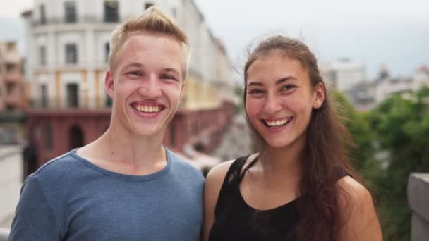 Счастливые смешанная раса парень и девушка улыбаются на городской улице летом — стоковое видео