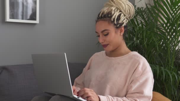 Evde kanepe üstünde laptop üzerinde çalışan genç kadın öğrenci — Stok video