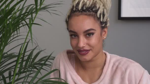 Beautiful sensual young woman smiling near leaves of houseplant — Stock Video