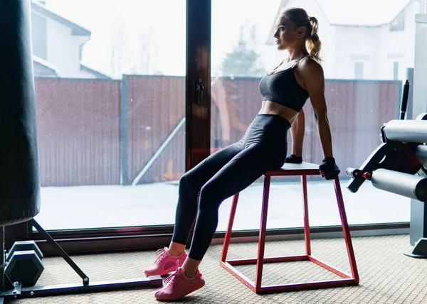 Fitness vrouw met perfect slank en gespierd lichaam poseren in sportschool in de buurt van venster — Stockfoto