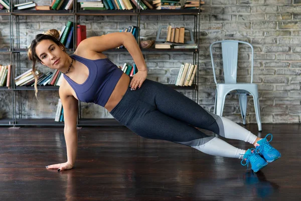 Fitness mladá žena, která dělá boční prkna cvičení doma — Stock fotografie