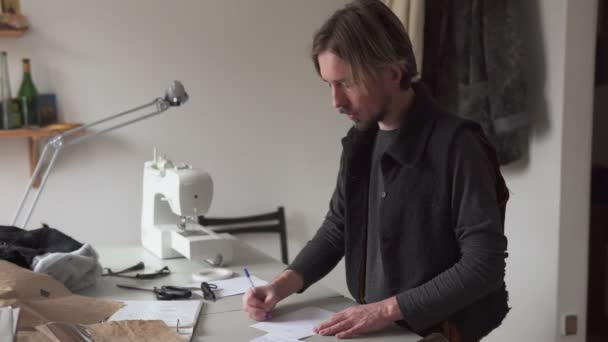 Мужской портной рисует креативный эскиз одежды в мастерской — стоковое видео