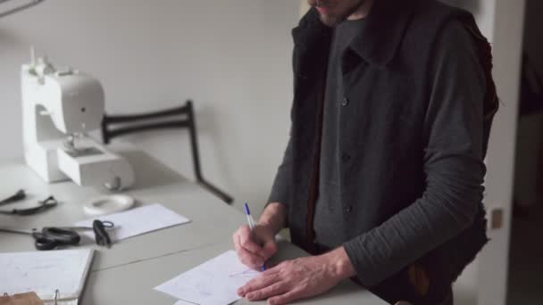 Homem alfaiate desenha padrão de roupa criativa na oficina — Vídeo de Stock