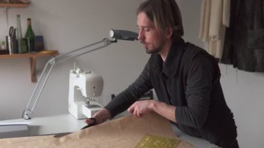 Adam terzi atölyesinde çalışırken giyim deseni yapım makas ile kesme