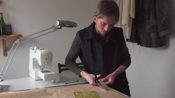 Hombre sastre con tijeras corta patrón de ropa de papel en el taller — Vídeo de stock