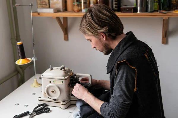 Hombre sastre trabajando en la máquina de peletería en taller Imágenes de stock libres de derechos