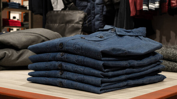 Синие джинсовые рубашки на столе в магазине одежды
