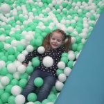 Kleines Mädchen spielt mit kleinen Bällen auf Spielplatz im Kinderzentrum