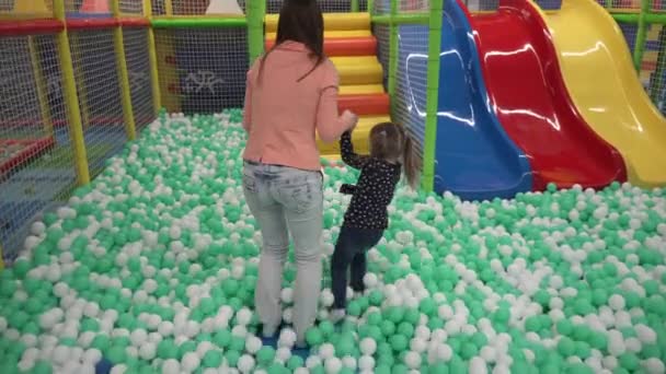 Madre e hija caminando sobre bolas en el patio de recreo en el centro de los niños — Vídeos de Stock