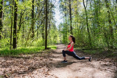Fitness kadın yaz ormanda bacak germe yapıyor
