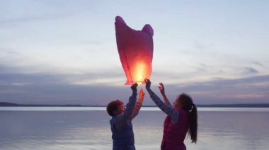 çocuklar gün batımında deniz tarafından gökyüzü fener başlatmak