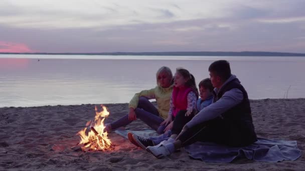 Rodina s dětmi mluvící táborním ohněm při západu slunce — Stock video