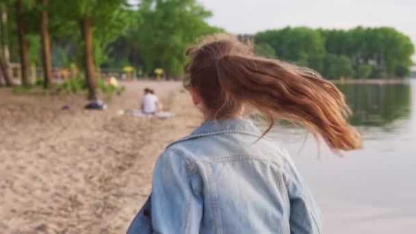 Девушка бежит вдоль песчаного берега в летний день — стоковое видео