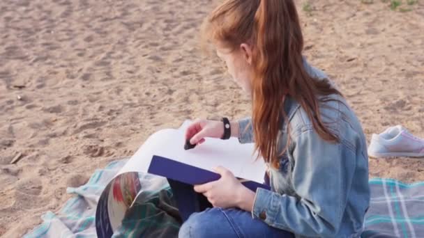 Girl drawing coal on paper at summer beach — Stock Video