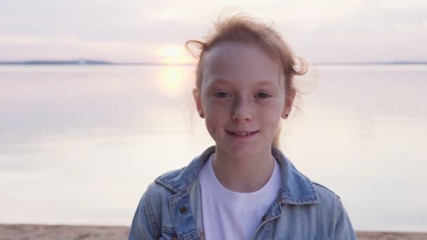Krásná rusovlasá dívka s pihami na moři při západu slunce