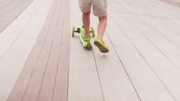 Маленький мальчик на скутере по улице в городе — стоковое видео