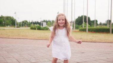 Küçük neşeli yalınayak kız su birikintisi atlama ve eğlenmek