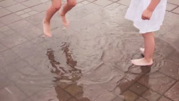 Enfants sautant et s'amusant dans la flaque d'eau dans la rue de la ville — Video