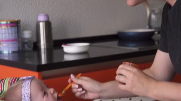 Счастливая мать кормит ребенка ложкой — стоковое видео