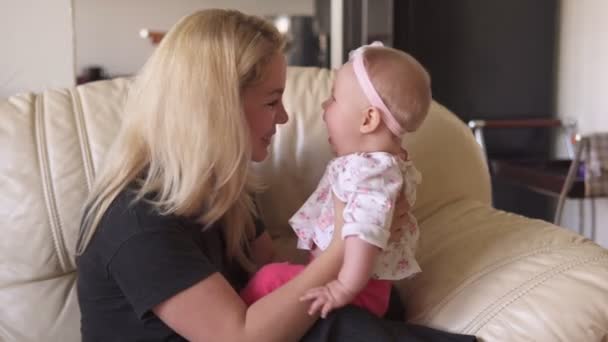 Мати і дитина дівчинка розважаються і посміхаються на дивані — стокове відео