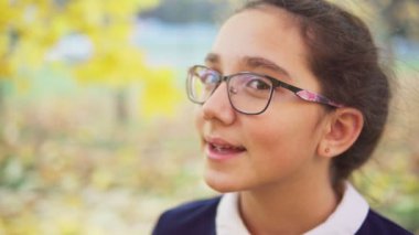 Mutlu genç kız dönüp sonbahar parkında kameraya bakıyor.