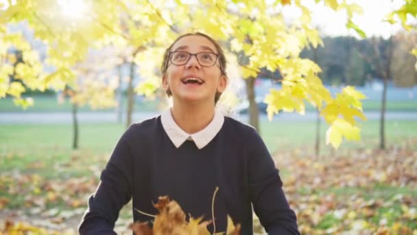 Gelukkig tiener meisje kotst omhoog bladeren in de herfst park — Stockvideo