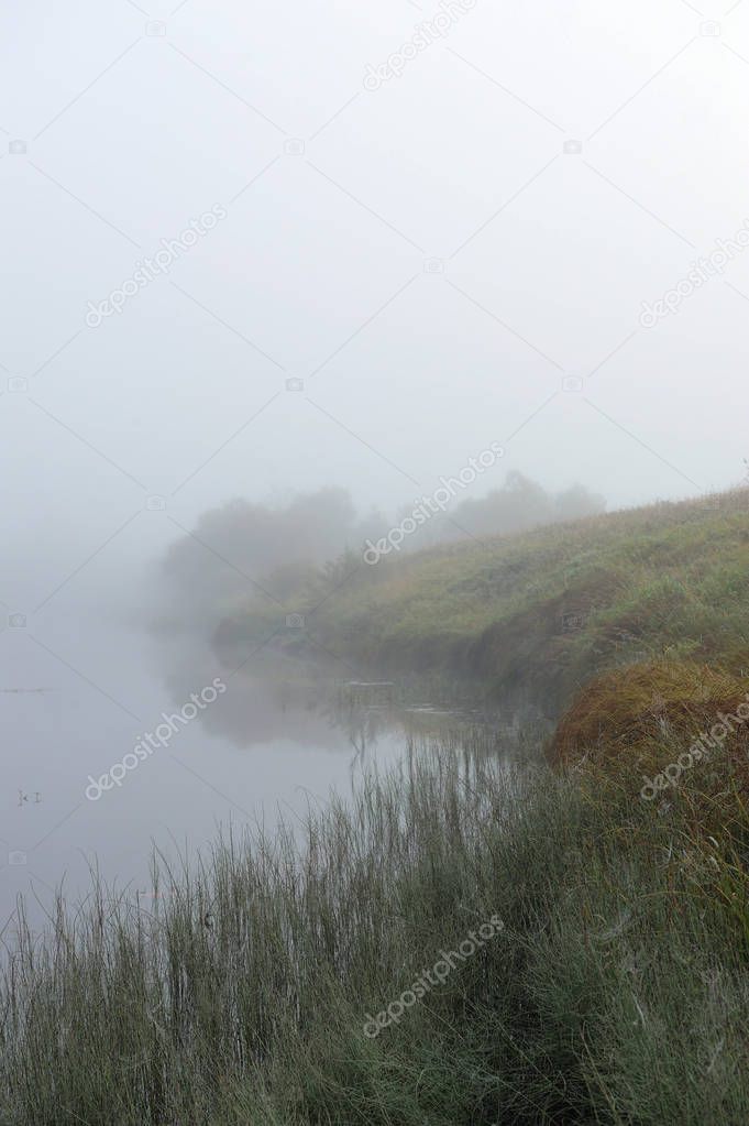 Early autumn morning. Dense fog envelops the surface of the river.