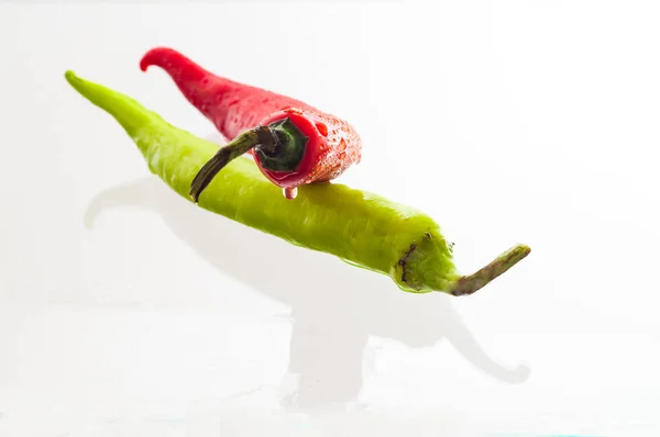 close up of red and green peppers on white background