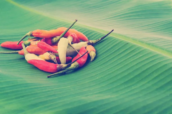 close up of peppers lying on banana leaf background