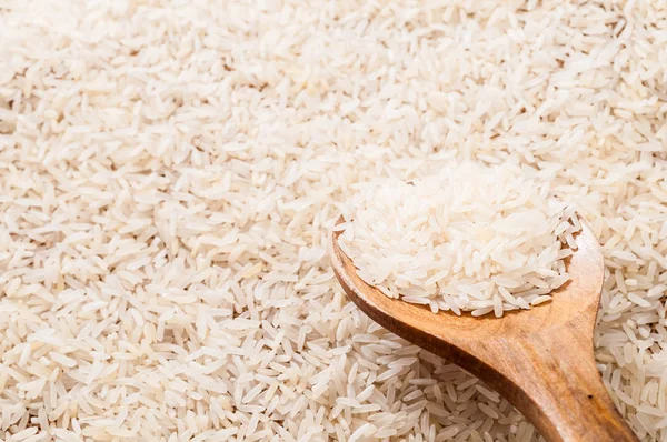 scattered on surface white rice with pile in wooden spoon