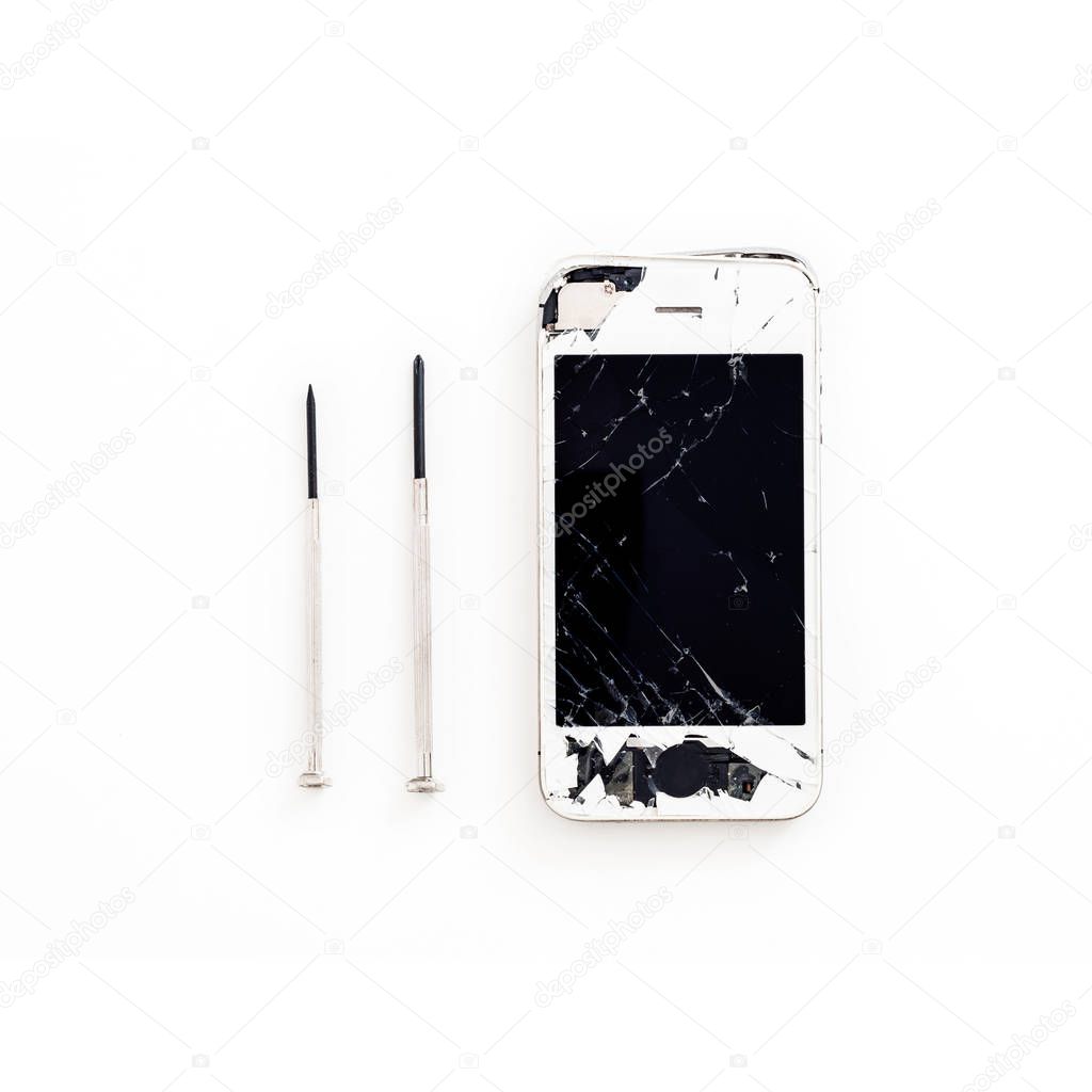 crashed smartphone with screwdrivers on white background
