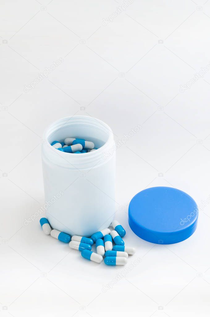 close up of colorful pills in white bottle on table 