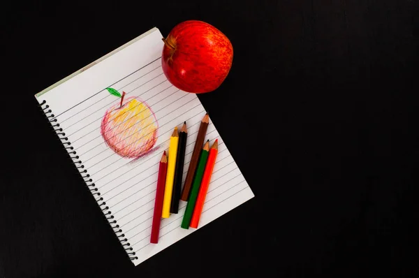 red apple and sketch drawing by pencils on black background