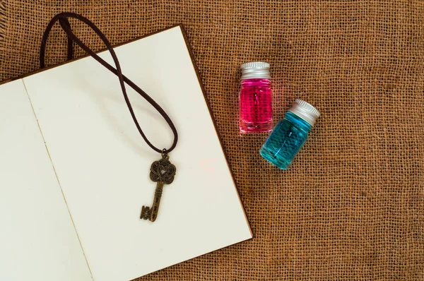 Две Бутылки Голубыми Розовыми Жидкостями Ключ Пустой Странице Ноутбука — стоковое фото