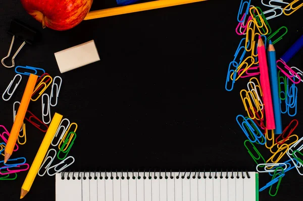 Frame from different school supplies with copy space on black background