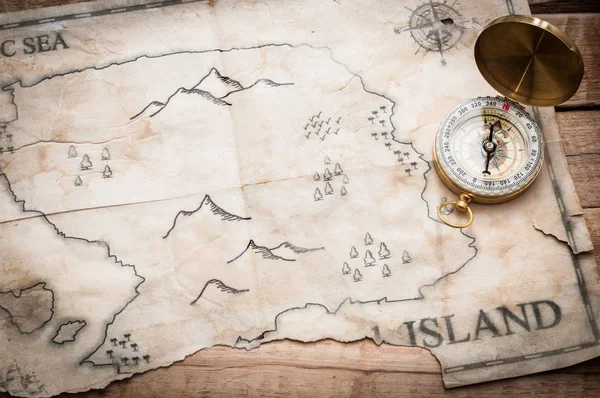 Compass and map of island on wooden background