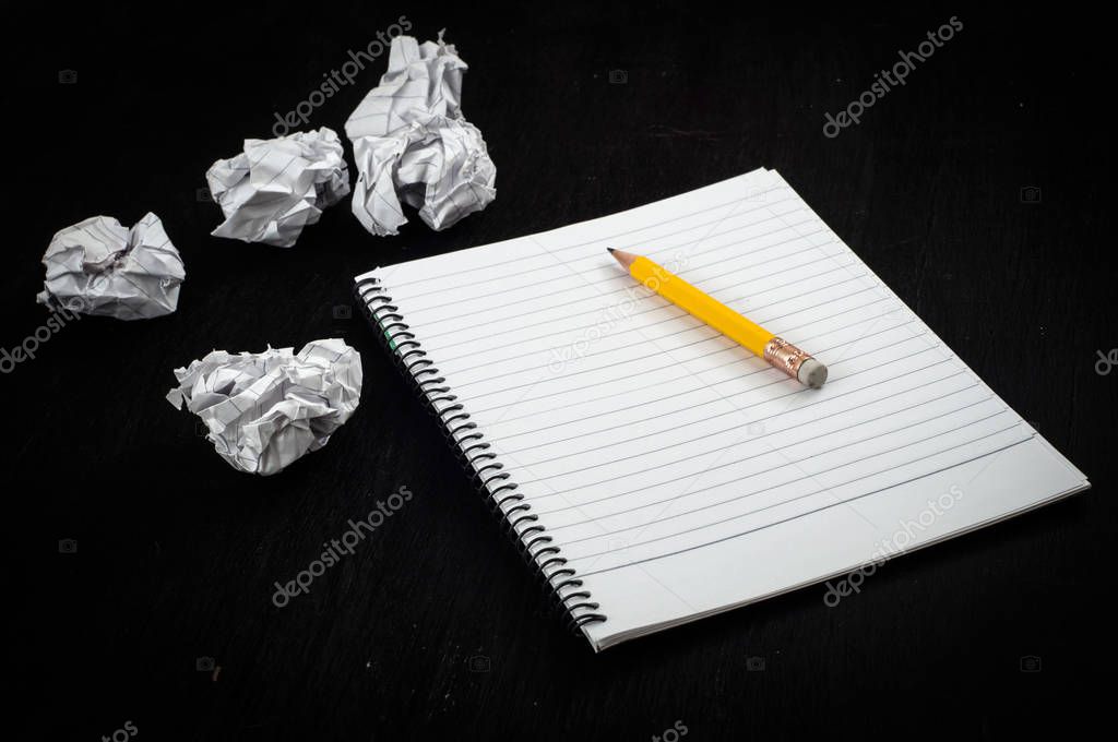 notebook with pencil and crumpled sheets on black background