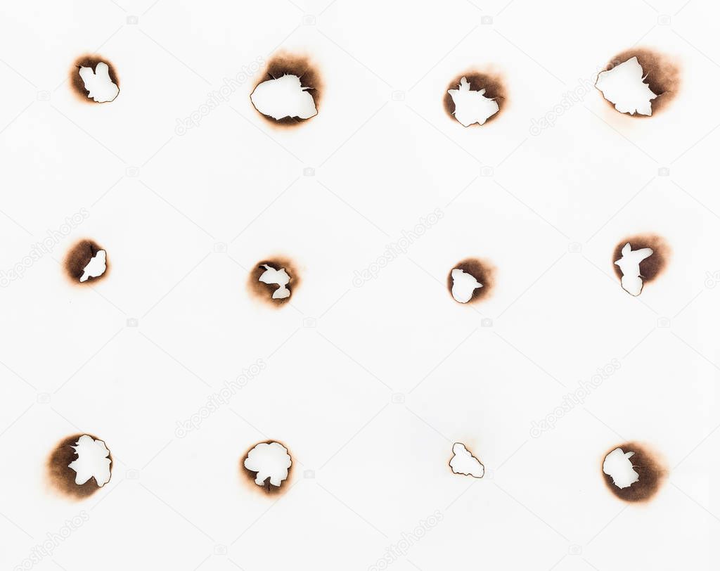 burning holes in white paper sheet on black background