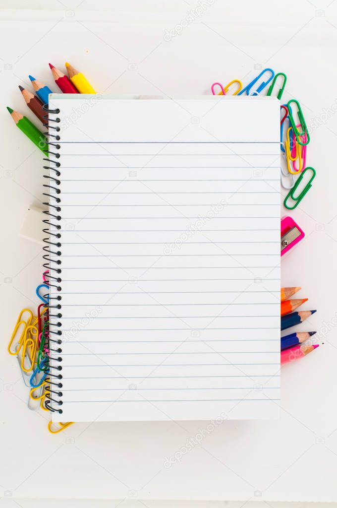 Notebook lying on colorful school supplies on white background 