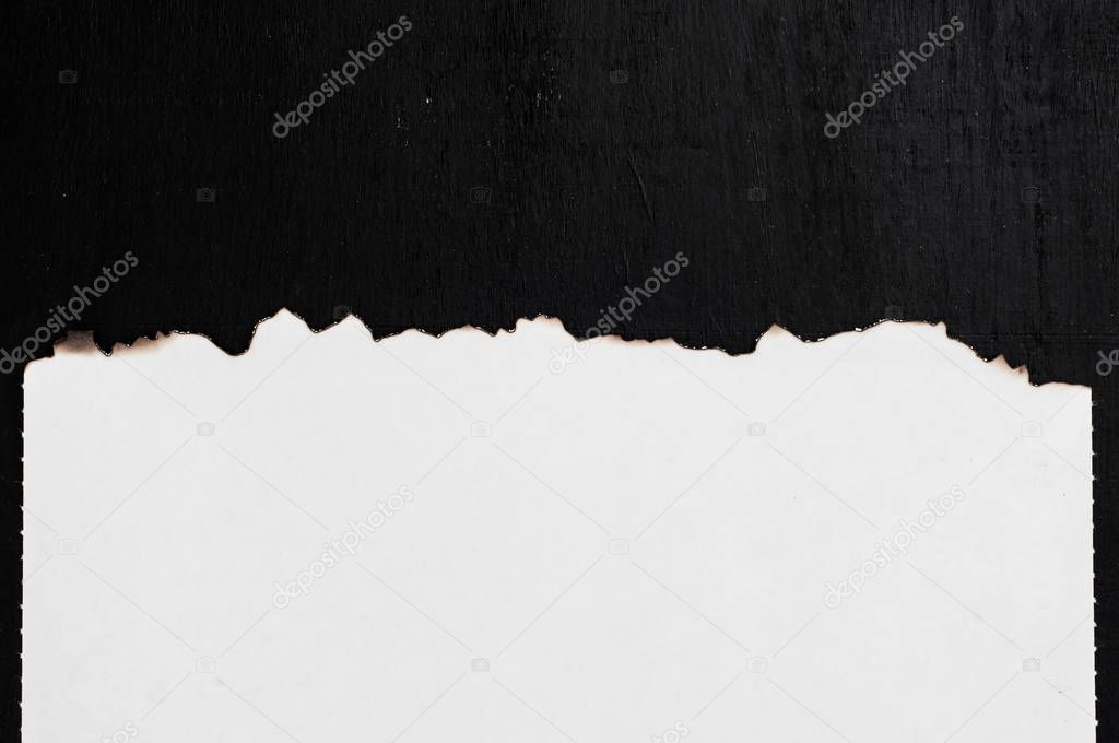 burning piece of white paper sheet on black background