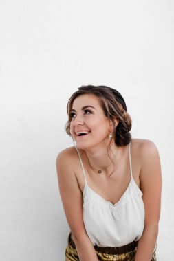 Beyaz elbiseli mutlu genç bir kadın izole edilmiş arka planda gülüyor ve gülümsüyor. Güzel makyajlı ve saç stilinde rüya gören güzel bir kadın. Stüdyo fotoğrafçılığı. Gülümseyen mutlu kız.  