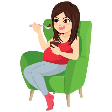 Beautiful brunette pregnant woman holding spoon eating chocolate ice cream sitting on green armchair craving concept clipart