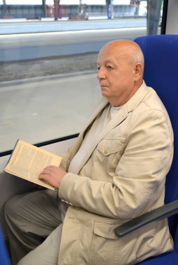 Düşünceli ihtiyar bir adamın elektrikli tren araba kitap okur