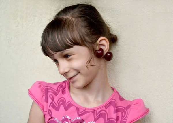 这个七岁的女孩带着甜樱桃浆果耳环在耳朵上 — 图库照片