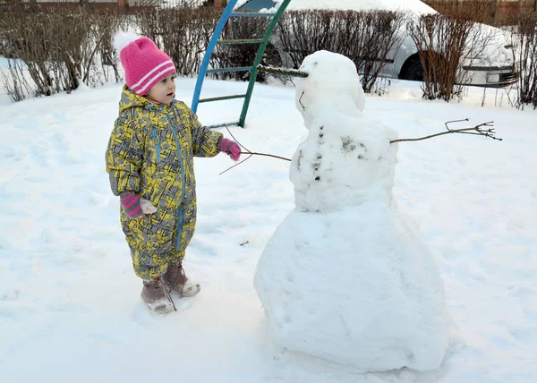 那个惊讶的小女孩看着雪人 — 图库照片